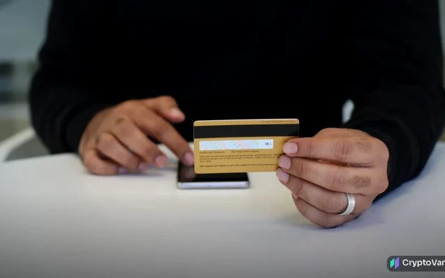 Person holding a gold crypto card next to a smartphone