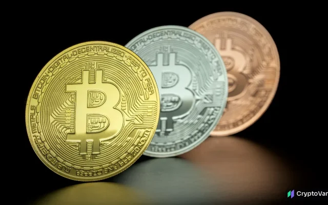 Gold, silver and copper bitcoin coins standing on a dark reflective surface