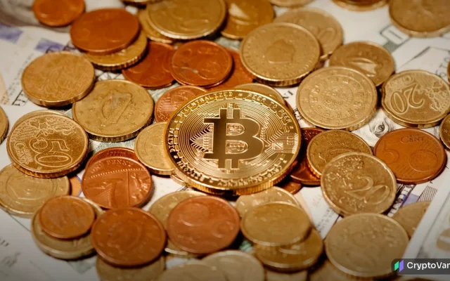 A gold bitcoin coin resting on a pile of copper and gold coins